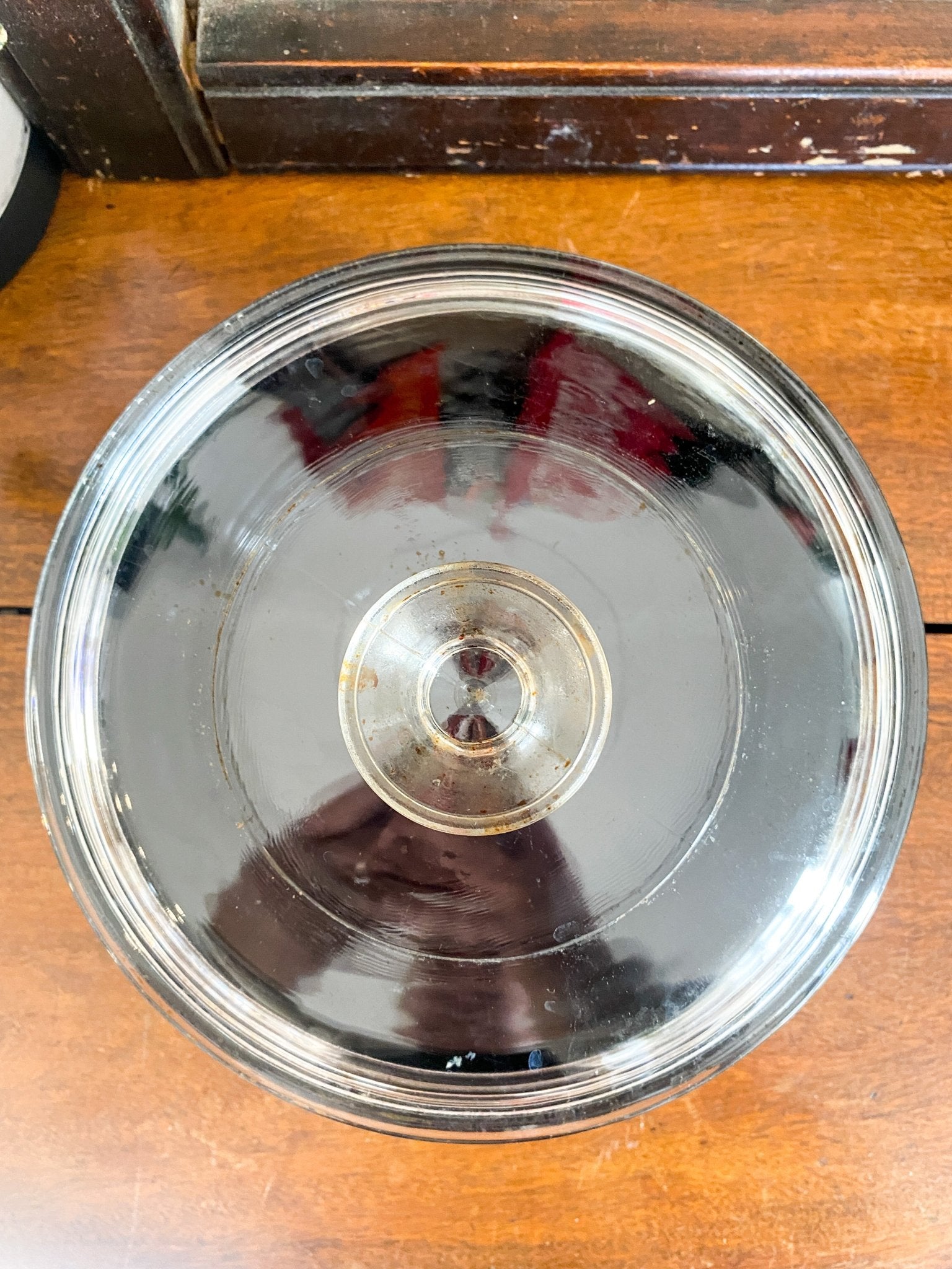 The dish is seen from an angle over top to clearly show the clear round lid. Note that there is some imperfections with baked in grease that is not easy to remove.