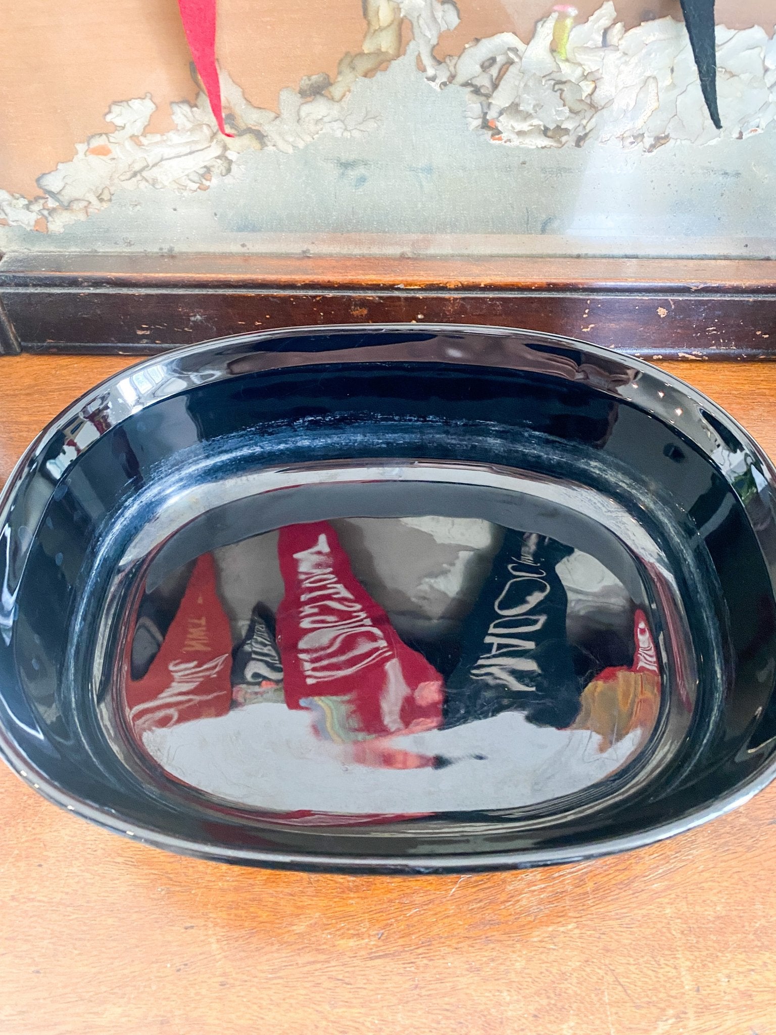 The black casserole dish is without its lid and shows the inside of the dish. There is a reflection of pennant flags. 
