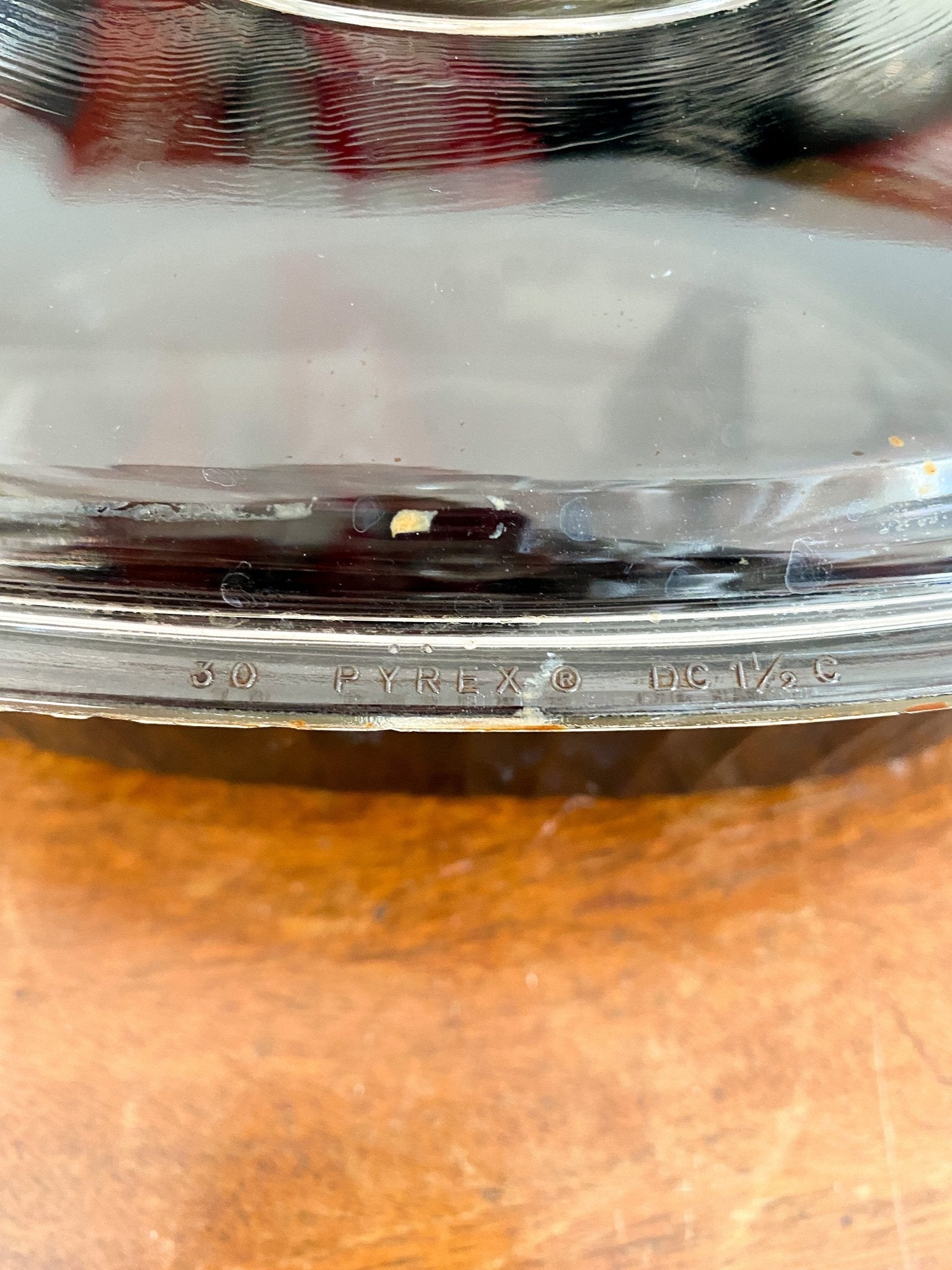 A close up of the clear glass lid on top of the black dish. The lid reads "30 Pyrex DC 1 and 1 half C"