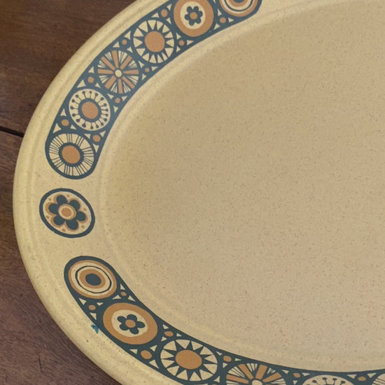 A close up of the tray from all angles, shows the black outlined flowers intimately with their different patterns and filled in the burnt orange colour. The woman then takes the tray to show the size of the tray and the back of it.