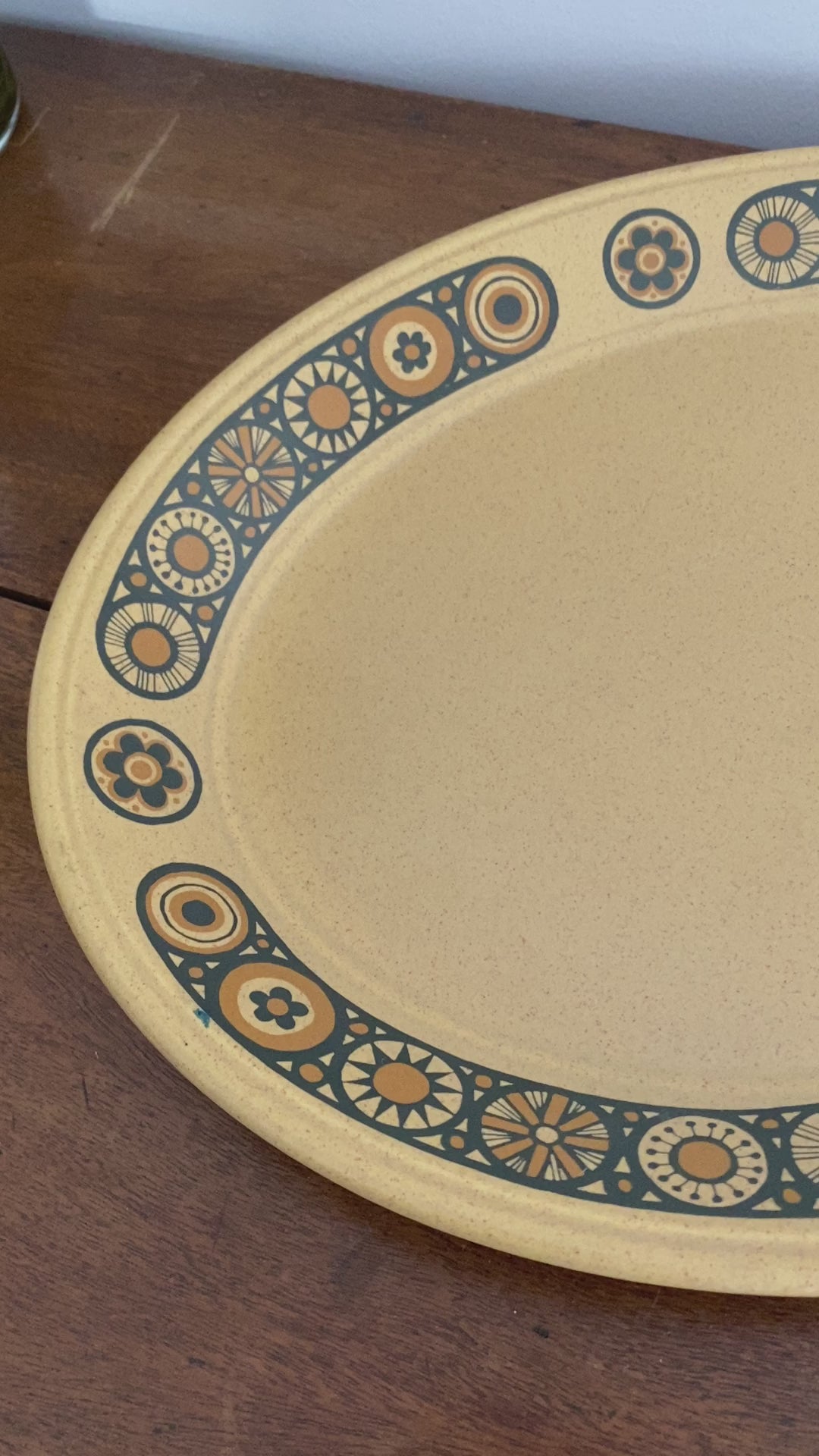 A close up of the tray from all angles, shows the black outlined flowers intimately with their different patterns and filled in the burnt orange colour. The woman then takes the tray to show the size of the tray and the back of it.