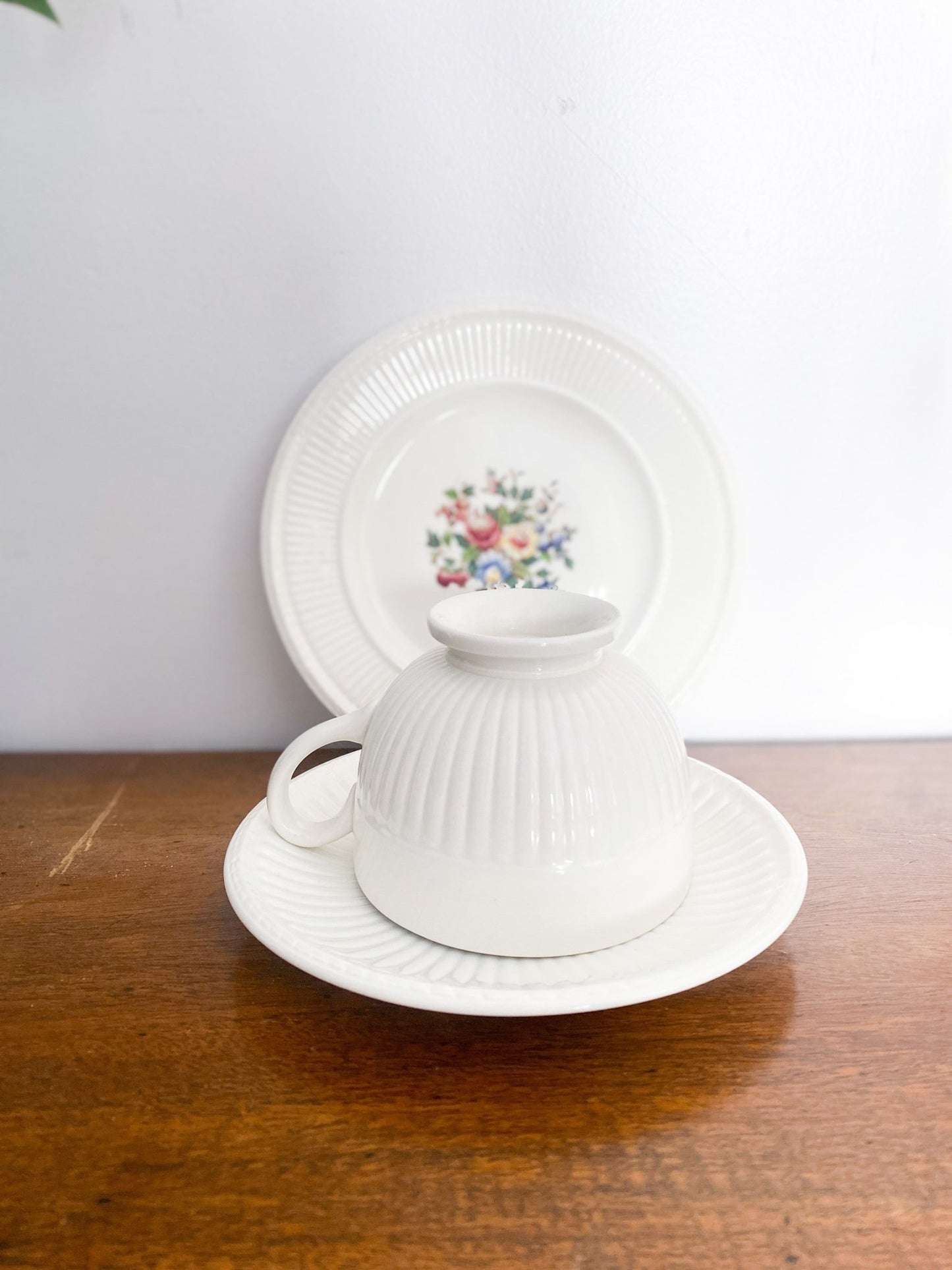 The teacup sits on top of the saucer upside down with the lunch plate out of focus on the back. The lunch plate shows the floral pattern in the centre. 